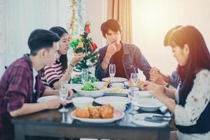 jantar com grupo asiático de melhores amigos desfrutando de bebidas à noite enquanto está sentado à mesa de jantar na cozinha juntos foto