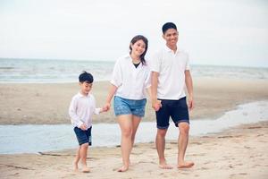 pais ativos e atividades ao ar livre de pessoas nas férias de verão e férias com crianças. filho e família felizes caminham com diversão do mar do sol na praia de areia. foto