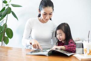 mãe está ensinando a filha a ler um livro. foto