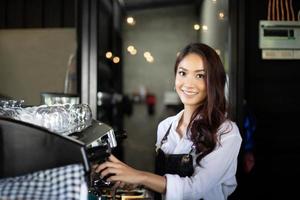 Barista de mulheres asiáticas sorrindo e usando a máquina de café no balcão da cafeteria - conceito de café de comida e bebida de proprietário de uma pequena empresa de trabalho mulher foto