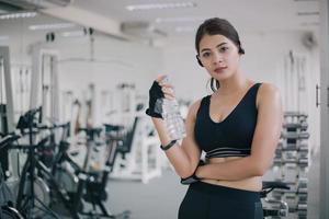 mulher desportiva Ásia bebendo água após exercícios no ginásio. fitness - conceito de saudável foto