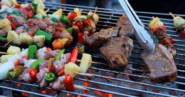 Grupo de amigos asiáticos fazendo churrasco ao ar livre no jardim, rindo com bebidas alcoólicas de cerveja à noite foto