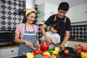 família feliz tem pai, mãe e sua filha cozinhando juntos na cozinha foto