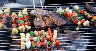 Grupo de amigos asiáticos fazendo churrasco ao ar livre no jardim, rindo com bebidas alcoólicas de cerveja à noite foto