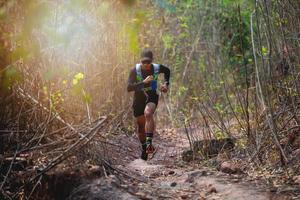 um homem corredor de trilha. e pés de atleta usando sapatos esportivos para trilha na floresta foto