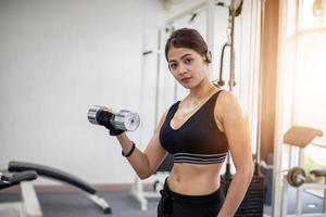 linda musculoso apto mulher exercitando construção de músculos e fitness mulher fazendo exercícios no ginásio. fitness - conceito de estilo de vida saudável foto