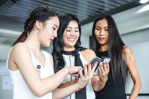 empresárias asiáticas com parceiro discutem sobre os detalhes do trabalho em smartphone e mulheres de negócios sorrindo