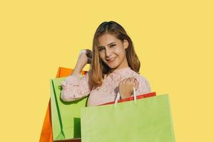 mulheres asiáticas linda garota está segurando sacolas de compras e sorrindo em fundo amarelo foto
