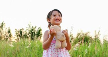 meninas asiáticas jogando ursinhos de pelúcia e rindo feliz no prado no verão na natureza foto