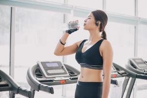 mulher desportiva Ásia bebendo água após exercícios no ginásio. fitness - conceito de saudável foto