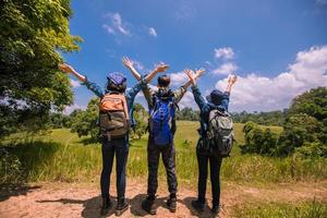 grupo asiático de jovens com mochilas de amigos caminhando juntos e amigos felizes levantando os braços e curtindo uma bela natureza e torcendo, relaxe na viagem do conceito de férias foto