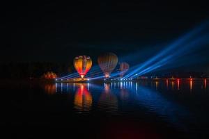 balões de ar quente coloridos voando sobre o rio no festival noturno foto