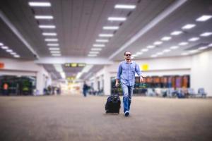 viajante de homem asiático com malas andando e transporte em um aeroporto foto