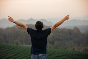 homens viajantes de liberdade em pé com os braços levantados e desfrutando de uma bela natureza e torcendo jovens ao pôr do sol, relaxe o tempo em viagens de conceito de férias foto