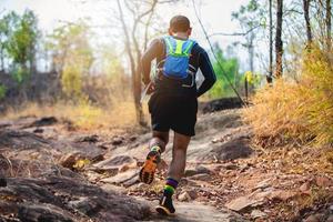 um homem corredor de trilha. e pés de atleta usando sapatos esportivos para trilha na floresta foto