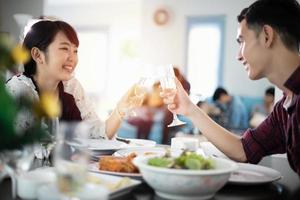 jovem casal asiático desfrutando de um jantar romântico bebidas à noite enquanto está sentado à mesa de jantar na cozinha juntos foto