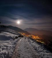 aldeia de montanha nevada à noite com a lua foto