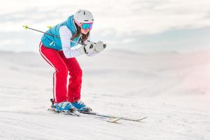 menina esquiadora em posição de descida foto
