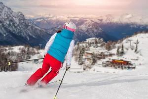 garota esportiva esquiando em direção à cabana alpina foto