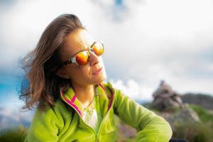 retrato de mulher descansando nas montanhas olhando o sol com óculos foto