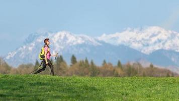 menina caminhadas nas montanhas com contrastes de primavera de prados verdes e neve nas montanhas foto