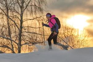 uma jovem desportiva corre com raquetes de neve foto