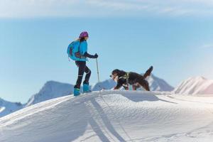 garota no topo de uma montanha com esquis e seu cachorro foto