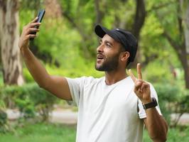 tirando selfie usando celular e mostrando sinal de vitória foto