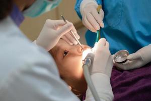 jovem dentista e assistente dental fazendo procedimento para tratar cárie dentária para menina na clínica