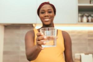 mulher negra mostrando um copo cheio de água foto