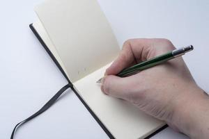 mãos de um homem segurando um caderno e uma caneta em um fundo branco. foto