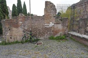 a bicicleta está acorrentada a um poste de luz em uma parede de tijolos. foto