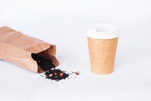 xícara de café de materiais reutilizáveis com chá preto em um saco orgânico em fundo branco. conceito de desperdício zero foto