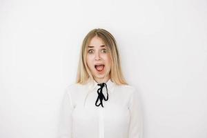 retrato mulher loira vestindo camisa branca elegante sobre fundo branco espantado e surpreso olhando para longe e abrindo a boca. cópia, espaço vazio para texto foto