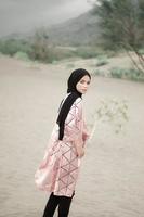 linda modelo feminina islâmica vestindo moda hijab, um vestido de noiva moderno para mulher muçulmana caminha pela areia e pelo mar. um modelo de menina asiática usando hijab se divertindo na praia. foto pré-casamento