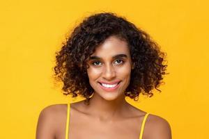 feliz sorrindo cabelo encaracolado linda mulher olhando para câmera isolada em fundo amarelo foto