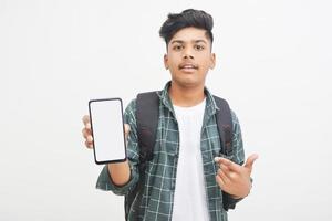 jovem estudante universitário indiano mostrando a tela do smartphone em fundo branco. foto