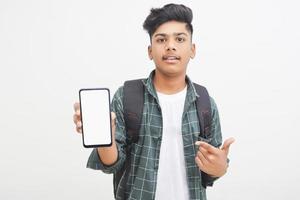 jovem estudante universitário indiano mostrando a tela do smartphone em fundo branco. foto