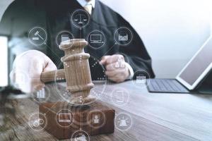 conceito de justiça e direito. juiz masculino em um tribunal batendo o martelo, trabalhando com teclado de encaixe de computador tablet digital na mesa de madeira, diagrama de ícones gráficos de interface virtual