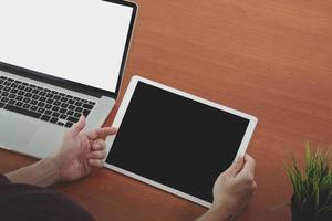 mão de empresário trabalhando com tela em branco novo laptop de computador moderno e tablet digital profissional na mesa de madeira como conceito foto