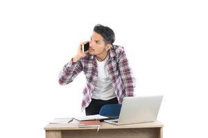 jovem empresário falando no telefone enquanto trabalhava no laptop no escritório, tempo ocupado com trabalho isolado no fundo branco. foto