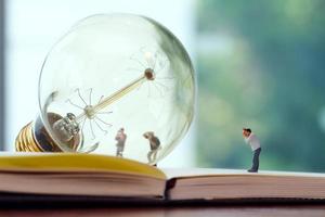 conceito de ideia criativa - fotógrafo em miniatura com lâmpada vintage no caderno de papel aberto foto