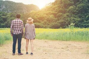 casal jovem hippie dando um passeio no campo de flores bonitas. foto