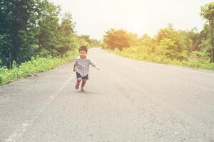 menino feliz em movimento, sorridente correndo na rua. foto