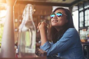 mulher pensativa jovem hippie com óculos, sentado à mesa no café. foto