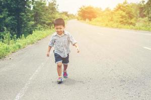 menino feliz em movimento, sorridente correndo na rua. foto