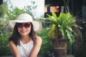 retrato de mulher encantadora relaxante na espreguiçadeira ao ar livre com chapéu e óculos. foto