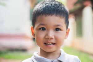 feche o retrato de menino asiático sorrindo no parque. foto