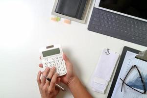 vista superior da mão do empresário trabalhando com finanças sobre custo e calculadora e latop com celular na mesa no escritório moderno foto