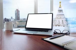 local de trabalho de escritório com laptop e telefone inteligente na mesa de madeira e fundo desfocado da cidade de londres foto